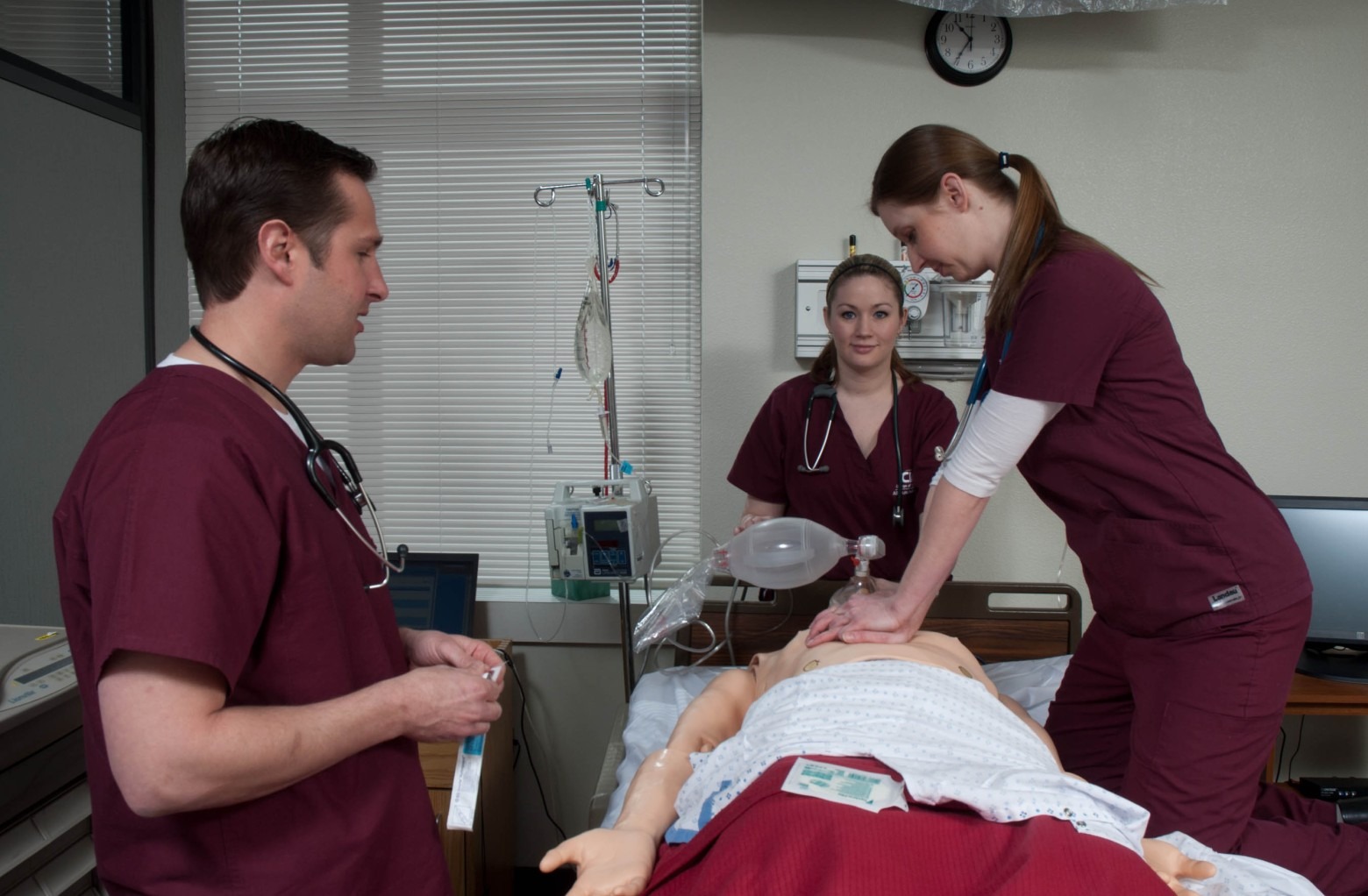 Three nursing students practicing CPR in medical classroom