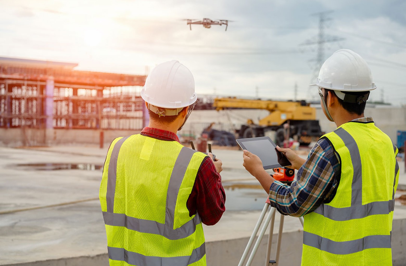 Two construction workers surveying a job site with a drone.