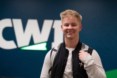 Student wearing a backpack next to a CWI-branded wall