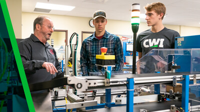CWI instructor with students learning on a packaging machine.