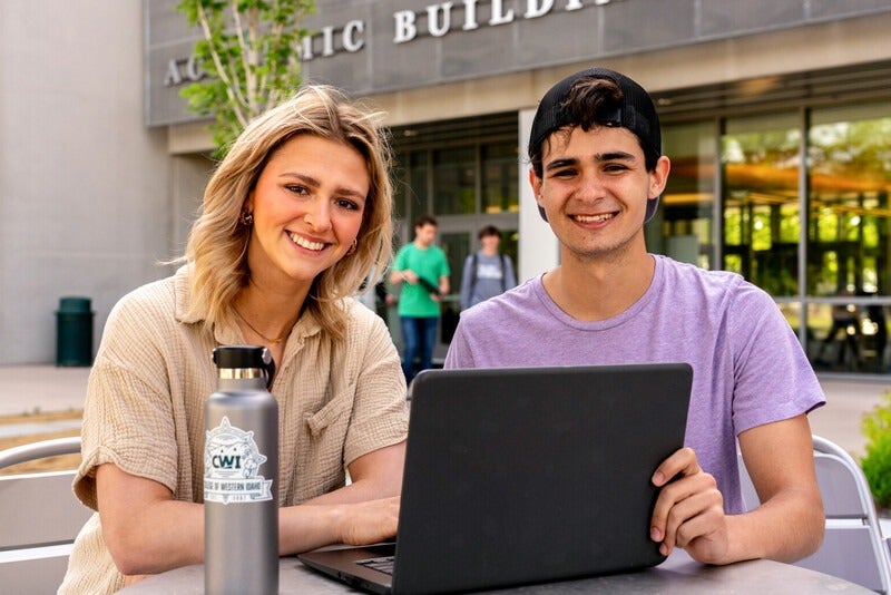 Students with laptop outside the Academic building