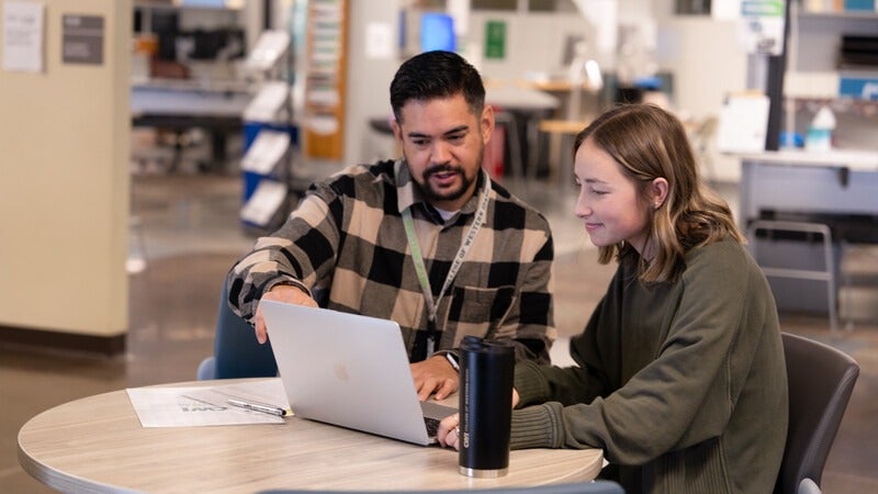 Advisor helping a student on a laptop
