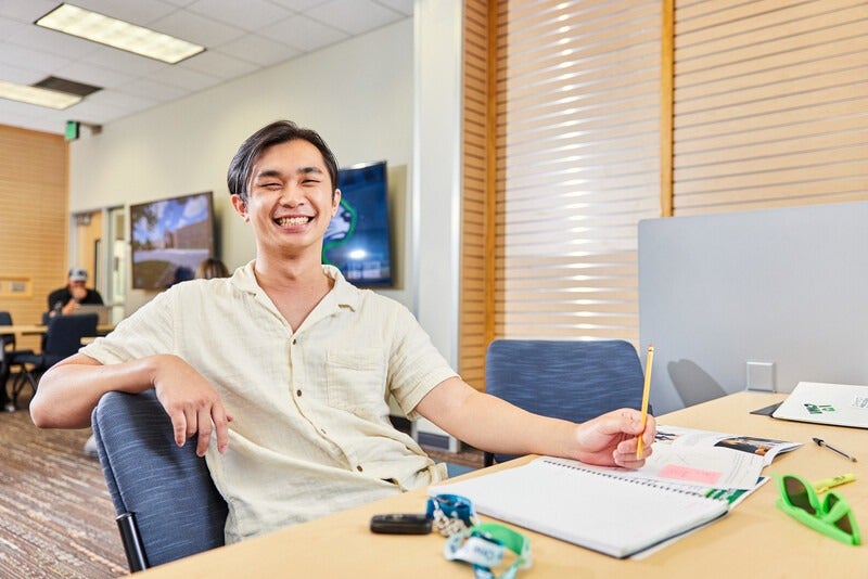 Student studying on campus smiling at the camera