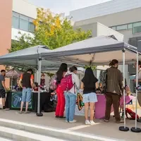 Students gather around two tables and two tents