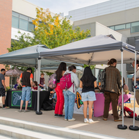 Students gather around two tables and two tents