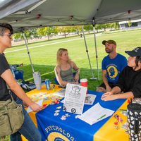 Three people sitting at a table talking to visitor