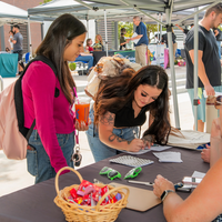 Two students visit booth and sign a paper