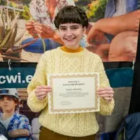 Student holds up scholarship certificate in front of CWI banner