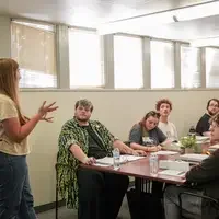 Group of people sit at table listening to speaker