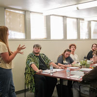 Group of people sit at table listening to speaker