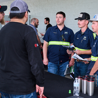 Three students chatting with employers with papers