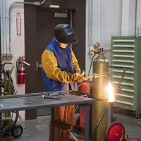 Person welding near table and tank