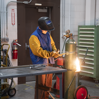 Person welding near table and tank