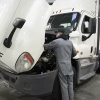 Person in front of semi truck with its hood open