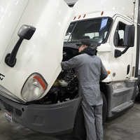 Person in front of semi truck with its hood open
