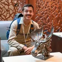 Student sits in front of metal Moose head sculpture