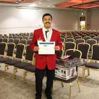 Student in red jacket with medal and holding a certificate