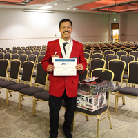 Student in red jacket with medal and holding a certificate