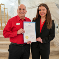 Two people holding a signed proclamation on the Capitol steps