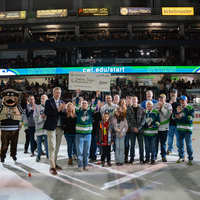 Group of people on the ice with one person holding up a large check