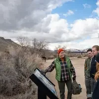 Students viewing sign in front of hill