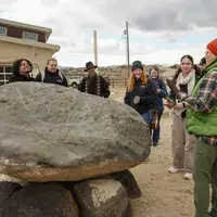 Students and instructor surround a rock 