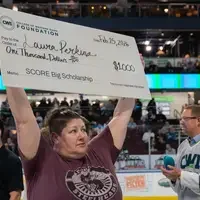 Laura Perkins holds up a giant check