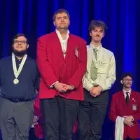Student stands on podium wearing a medal
