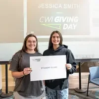 Two students hold thank you sign for student clubs