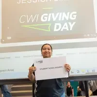 Student holding sign expressing support for student scholarships
