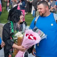 Graduate with family member and flowers