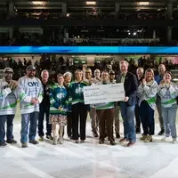 large group of people hold a check on the ice