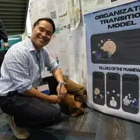 Student squats next to their poster competition