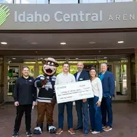 group of people hold Idaho Central Credit Union check