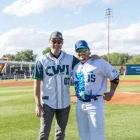 Mike Pena stands with a baseball player in the field 