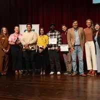 Award winners and panelists stand on stage