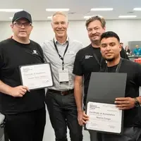 Four people stand in CWI classroom with certificates