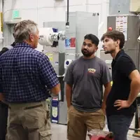 Instructor speaking to students in front of HVAC equipment