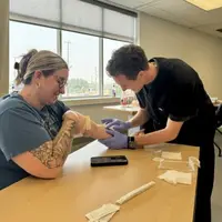 Student sticking arm out and another student practicing IV exercises 