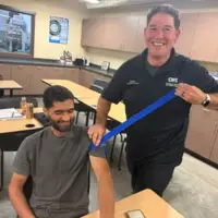 An instructor hold a blue wrap next to a seated student