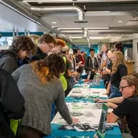 Crowds of people talk to people at desks and tables