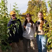 Three people stand in a garden