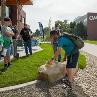 Instructor showcasing equipment near rocks and in front of students