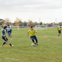 Soccer player dribbling ball between players