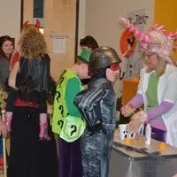 Students playing games with kids in costumes at the Halloween party.
