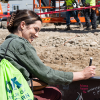 A woman smiles as she signs her name onto a construction beam.