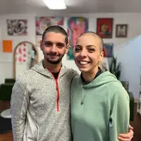 A couple, one with hair loss from chemotherapy, pose for a photo.