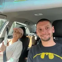 A couple, one with hair loss from chemotherapy, snap a photo in a car.