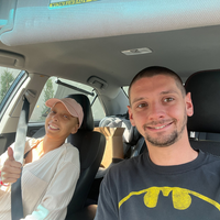 A couple, one with hair loss from chemotherapy, snap a photo in a car.