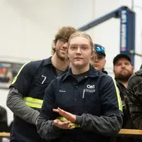 A CWI student, surrounded by others, applaud during an event.